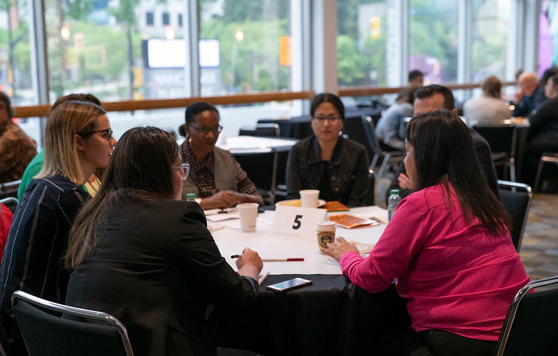 A group of designers seated at a table, having a conversation.