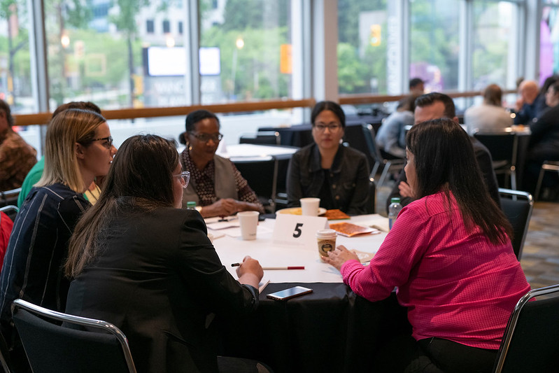 A group of designers seated at a table, having a conversation.