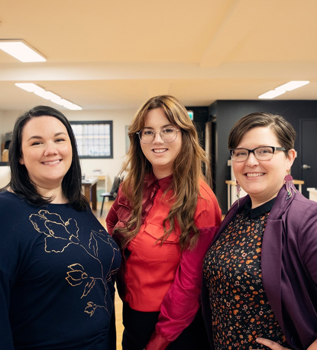 Three women stand and pose for a photo