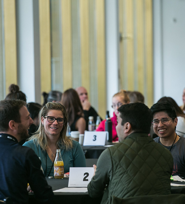 People sitting at a roundtable discussion. They are smiling and talking.