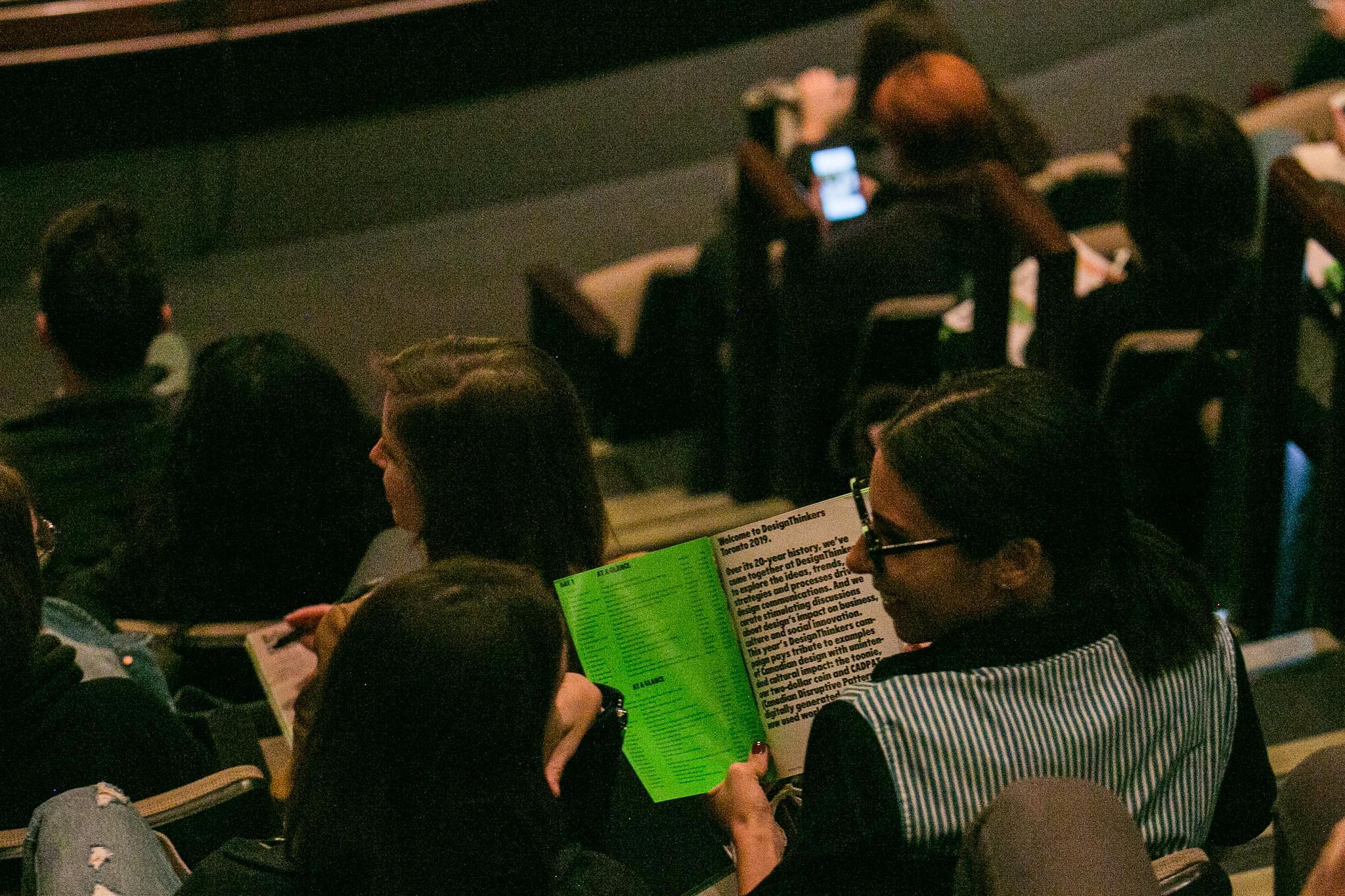 People reading a program at DesignThinkers Toronto.